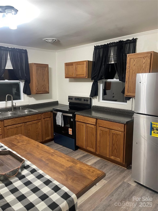 576 Morrow Motor Rd, Forest City, NC 28043 - kitchen featuring freestanding refrigerator, range with electric cooktop, light wood-style floors, brown cabinets, and dark countertops