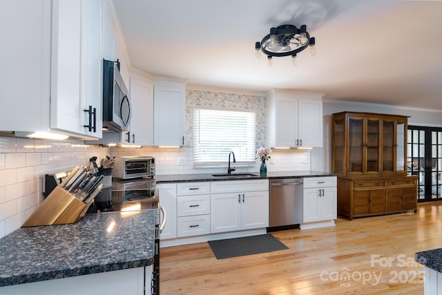 304 Sowers Ferry Rd, Salisbury, NC 28144 - kitchen with stainless steel appliances, white cabinetry, light wood finished floors, backsplash, and crown molding