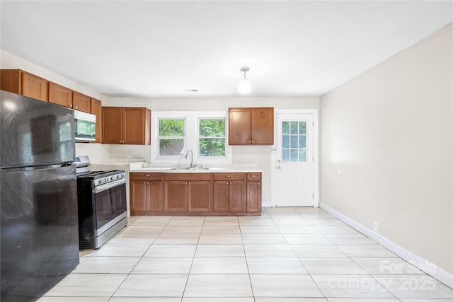 716 Wilson Rd, Salisbury, NC 28144 - kitchen featuring freestanding refrigerator, stainless steel stove, light countertops, and brown cabinetry