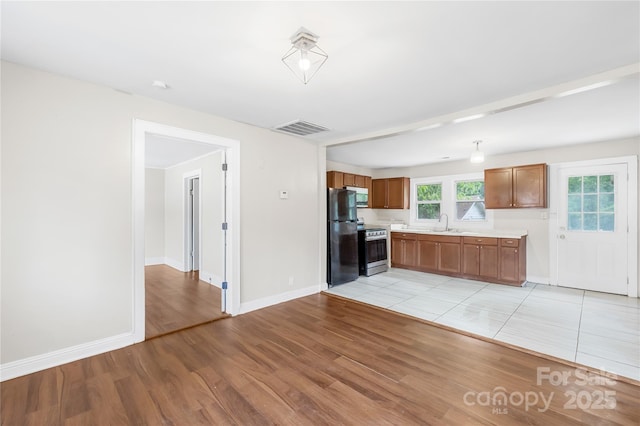716 Wilson Rd, Salisbury, NC 28144 - kitchen featuring stainless steel appliances, light countertops, light wood-style flooring, and brown cabinetry