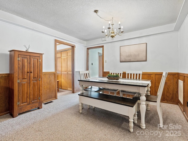 2212 Jb Denton Rd, Lancaster, SC 29720 - dining space featuring a wainscoted wall, a textured ceiling, a chandelier, light carpet, and wooden walls