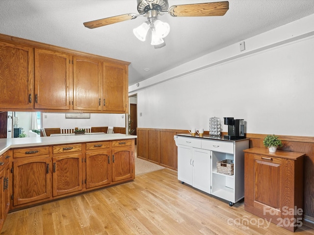 2212 Jb Denton Rd, Lancaster, SC 29720 - kitchen featuring brown cabinetry, wainscoting, ceiling fan, light wood-type flooring, and light countertops