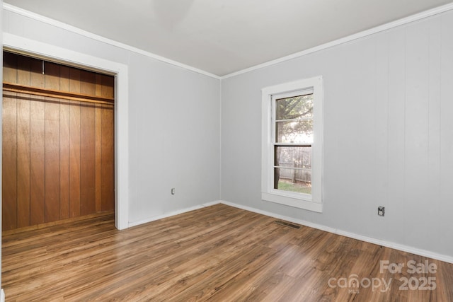 1302 1st Ave NW, Hickory, NC 28601 - unfurnished bedroom with wood finished floors, crown molding, a closet, and wooden walls