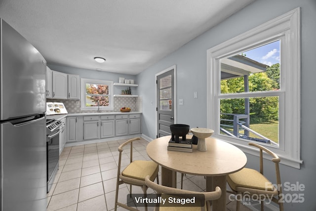 3422 Dublin Rd, Charlotte, NC 28208 - kitchen with appliances with stainless steel finishes, decorative backsplash, light tile patterned floors, light countertops, and gray cabinetry