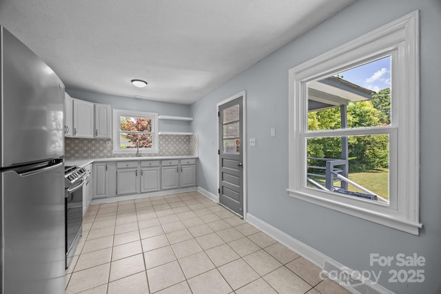 3422 Dublin Rd, Charlotte, NC 28208 - kitchen with appliances with stainless steel finishes, tasteful backsplash, light tile patterned floors, light countertops, and open shelves
