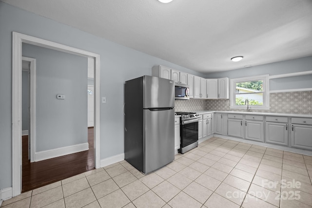 3422 Dublin Rd, Charlotte, NC 28208 - kitchen featuring stainless steel appliances, light countertops, light tile patterned floors, gray cabinetry, and open shelves