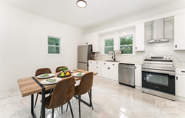 617 N Juniper Ave, Kannapolis, NC 28081 - kitchen featuring appliances with stainless steel finishes, wall chimney range hood, light marble finish floors, tasteful backsplash, and light countertops