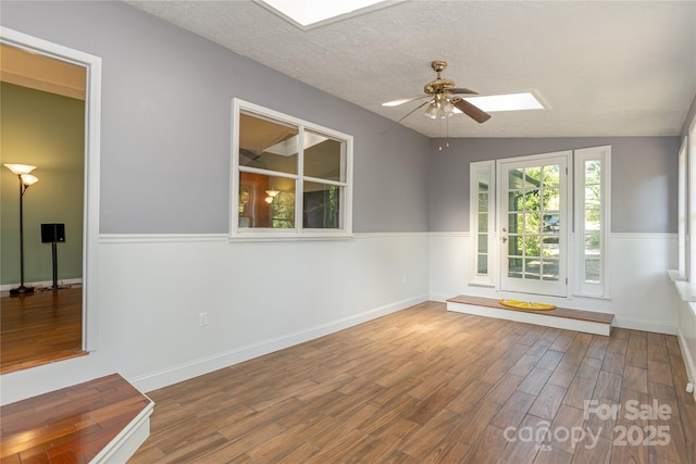 18 Peaceful Valley Ln, Flat Rock, NC 28731 - unfurnished room featuring a skylight, wood finished floors, a ceiling fan, vaulted ceiling, and a textured ceiling