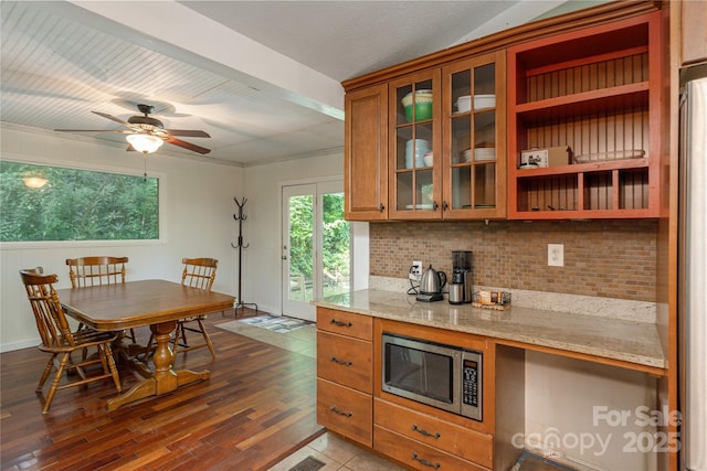 18 Peaceful Valley Ln, Flat Rock, NC 28731 - kitchen with stainless steel microwave, brown cabinets, tasteful backsplash, dark wood-style flooring, and light stone counters