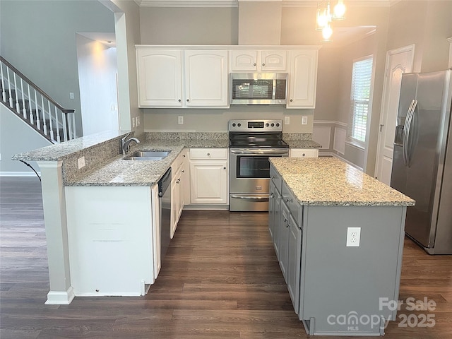 2834 Ritz Ln, Matthews, NC 28105 - kitchen with stainless steel appliances, a peninsula, white cabinets, light stone counters, and crown molding