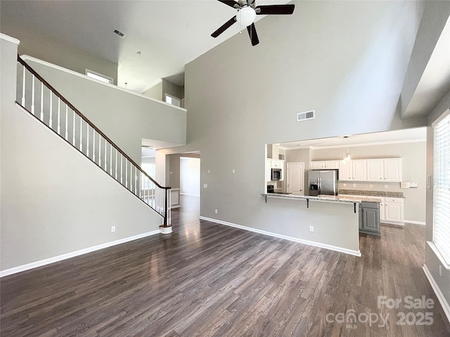 2834 Ritz Ln, Matthews, NC 28105 - unfurnished living room featuring a towering ceiling, a ceiling fan, stairway, and dark wood-style flooring