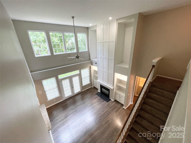 2834 Ritz Ln, Matthews, NC 28105 - unfurnished living room with dark wood-style flooring, stairs, a ceiling fan, a fireplace with flush hearth, and recessed lighting