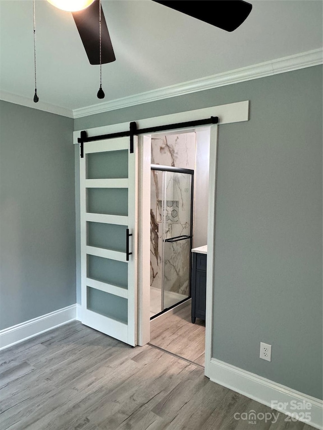 911 S Spencer Ave, Spencer, NC 28915 - unfurnished bedroom featuring a barn door, crown molding, wood finished floors, connected bathroom, and ceiling fan