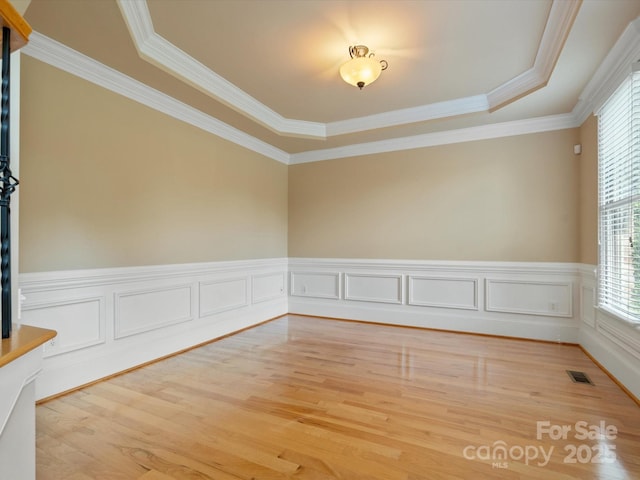 8407 Rolling Fields Rd, Mint Hill, NC 28227 - spare room with a tray ceiling, light wood-style flooring, ornamental molding, and a wainscoted wall