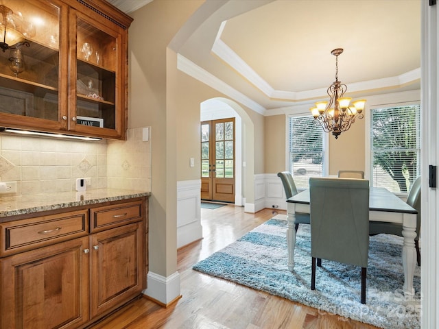 8407 Rolling Fields Rd, Mint Hill, NC 28227 - dining space featuring arched walkways, healthy amount of natural light, a chandelier, ornamental molding, and a wainscoted wall