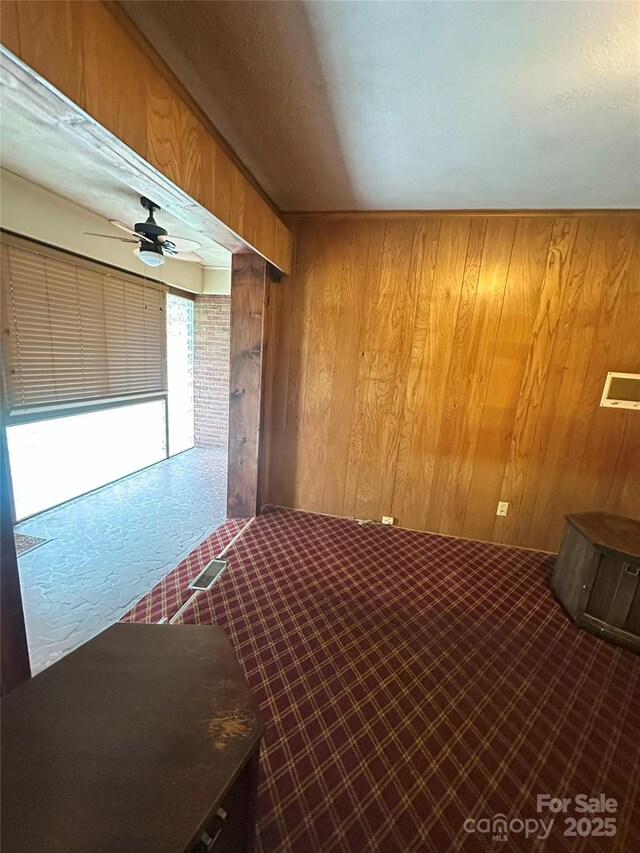 2128 Senior Dr, Charlotte, NC 28216 - unfurnished bedroom featuring wood walls, a ceiling fan, and dark carpet