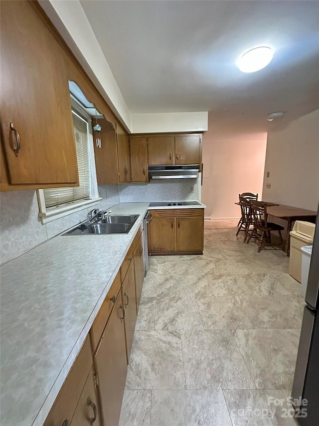 2128 Senior Dr, Charlotte, NC 28216 - kitchen with under cabinet range hood, light countertops, stainless steel dishwasher, and brown cabinetry