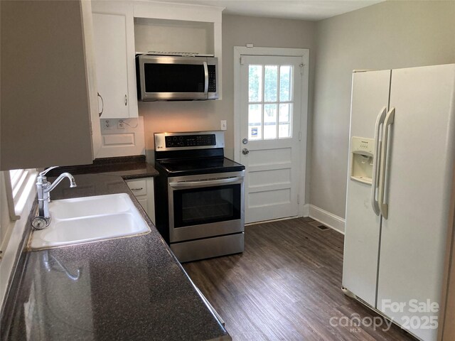 1162 Brighton Pl, Charlotte, NC 28205 - kitchen with stainless steel appliances, dark wood-style flooring, dark countertops, and white cabinetry