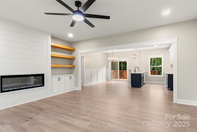 299 Collingswood Dr, Concord, NC 28027 - unfurnished living room with a glass covered fireplace, a chandelier, light wood-style floors, a ceiling fan, and recessed lighting