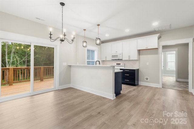 299 Collingswood Dr, Concord, NC 28027 - kitchen featuring white appliances, light countertops, light wood-type flooring, tasteful backsplash, and white cabinets