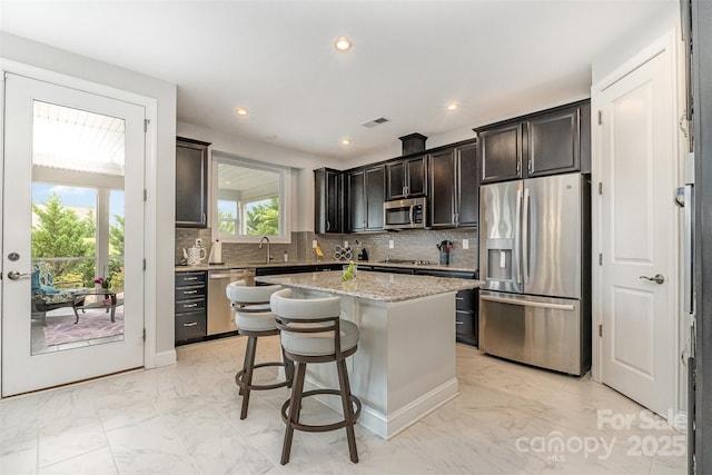 7025 Overjoyed Xing, Charlotte, NC 28215 - kitchen with stainless steel appliances, light marble finish floors, a kitchen island, backsplash, and recessed lighting