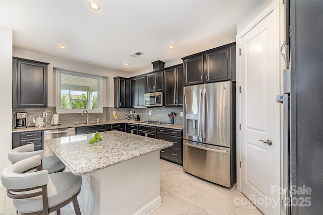 7025 Overjoyed Xing, Charlotte, NC 28215 - kitchen featuring appliances with stainless steel finishes, light marble finish floors, light stone countertops, a kitchen island, and decorative backsplash