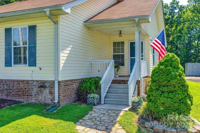 659 Primrose Ln NW, Concord, NC 28027 - view of exterior entry featuring covered porch, roof with shingles, and a yard
