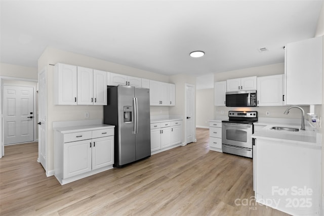 6907 Spandril Ln, Charlotte, NC 28215 - kitchen featuring stainless steel appliances, white cabinets, light wood-style floors, and light countertops
