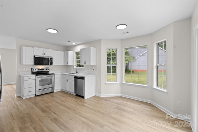 6907 Spandril Ln, Charlotte, NC 28215 - kitchen with appliances with stainless steel finishes, light countertops, white cabinets, and healthy amount of natural light