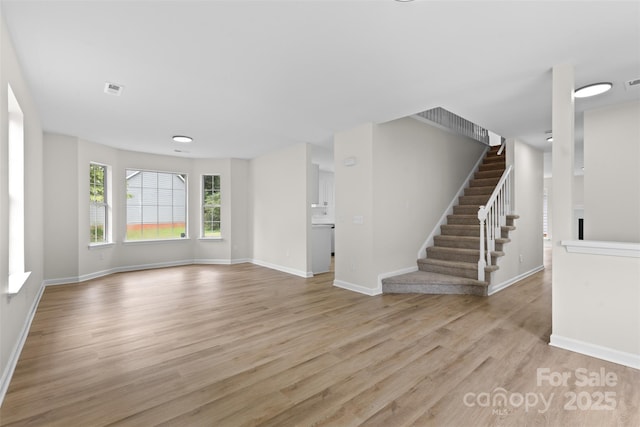 6907 Spandril Ln, Charlotte, NC 28215 - unfurnished living room with light wood finished floors and stairs