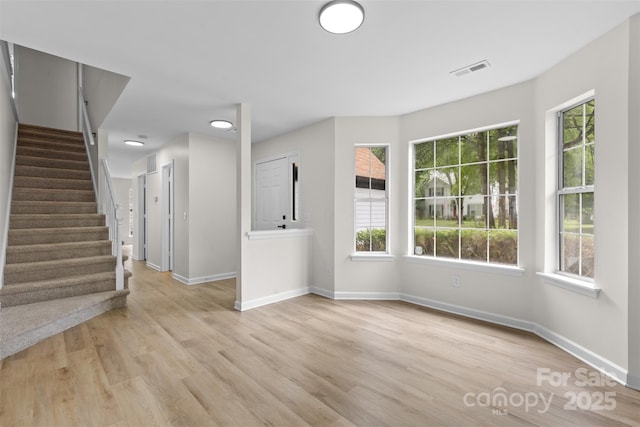 6907 Spandril Ln, Charlotte, NC 28215 - unfurnished living room featuring plenty of natural light, stairway, and light wood finished floors