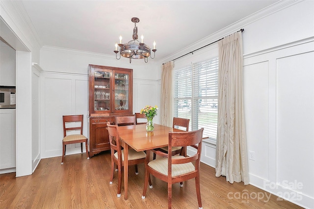 427 Lansdowne Rd, Charlotte, NC 28270 - dining area with a decorative wall, a chandelier, ornamental molding, and light wood finished floors