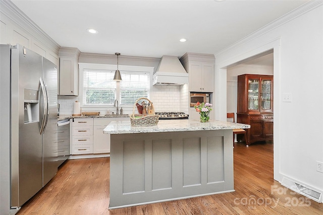 427 Lansdowne Rd, Charlotte, NC 28270 - kitchen featuring appliances with stainless steel finishes, custom range hood, ornamental molding, light wood-style floors, and backsplash