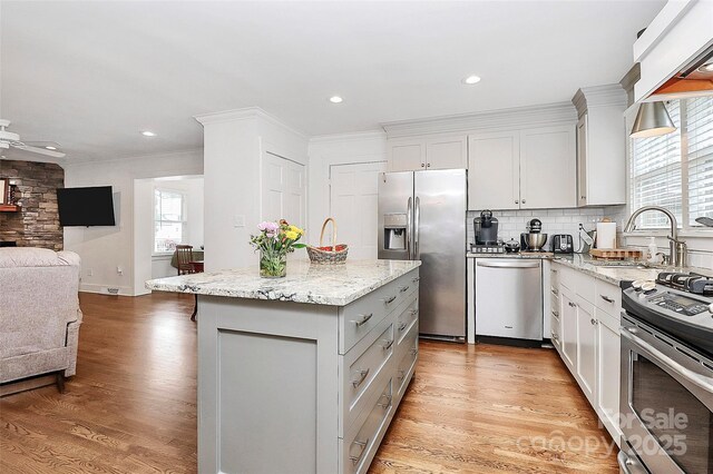 427 Lansdowne Rd, Charlotte, NC 28270 - kitchen with stainless steel appliances, open floor plan, a kitchen island, light wood-type flooring, and light stone counters