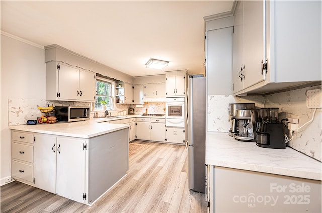 464 23rd Avenue Dr NE, Hickory, NC 28601 - kitchen with stainless steel appliances, light wood finished floors, a peninsula, decorative backsplash, and light countertops