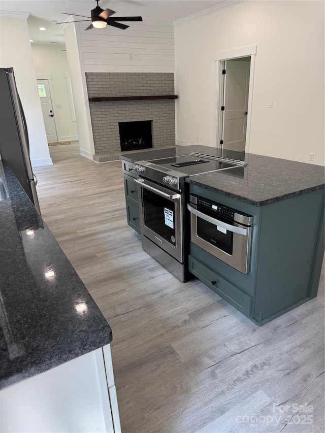 7187 Sherrills Ford Rd, Sherrills Ford, NC 28673 - kitchen featuring appliances with stainless steel finishes, light wood-type flooring, a ceiling fan, dark stone countertops, and crown molding