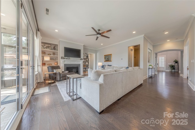 5266 Meadowcroft Way, Fort Mill, SC 29708 - living area featuring dark wood-style floors, arched walkways, a ceiling fan, crown molding, and a glass covered fireplace