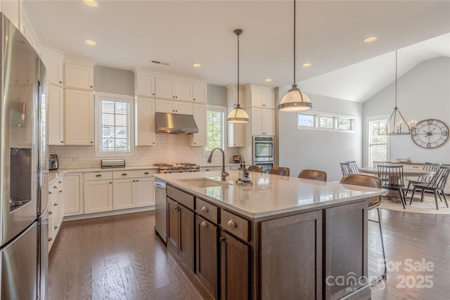 5266 Meadowcroft Way, Fort Mill, SC 29708 - kitchen featuring appliances with stainless steel finishes, under cabinet range hood, dark wood finished floors, tasteful backsplash, and vaulted ceiling