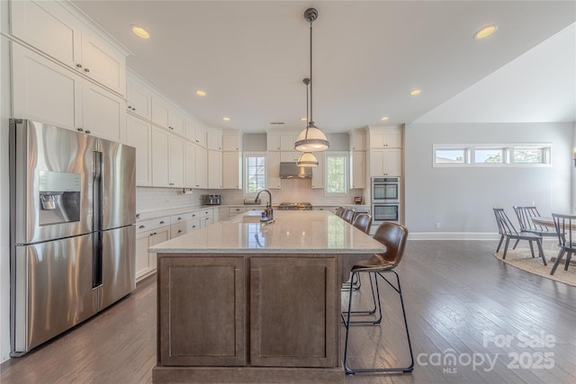5266 Meadowcroft Way, Fort Mill, SC 29708 - kitchen with appliances with stainless steel finishes, under cabinet range hood, tasteful backsplash, white cabinets, and a center island with sink