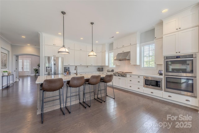 5266 Meadowcroft Way, Fort Mill, SC 29708 - kitchen with appliances with stainless steel finishes, under cabinet range hood, arched walkways, white cabinetry, and recessed lighting