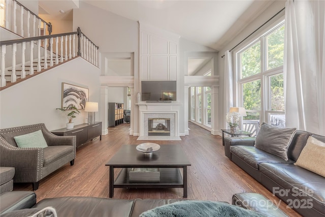 2836 Providence Spring Ln, Charlotte, NC 28270 - living room featuring high vaulted ceiling, wood finished floors, a fireplace with flush hearth, and stairway