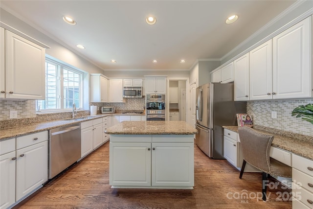 2836 Providence Spring Ln, Charlotte, NC 28270 - kitchen featuring appliances with stainless steel finishes, crown molding, decorative backsplash, a center island, and white cabinetry