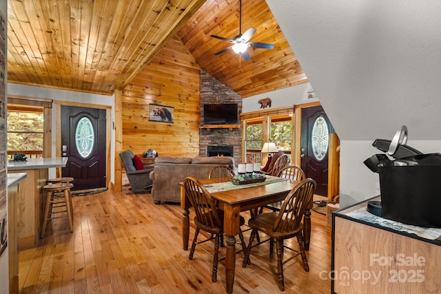 55 Kirkland Mountain Ln, Bryson City, NC 28713 - dining area featuring a stone fireplace, light wood-style floors, lofted ceiling, wooden walls, and a ceiling fan