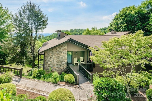 153 Country Ridge Rd, Laurel Park, NC 28739 - mid-century modern home featuring stone siding, roof with shingles, a chimney, and covered porch