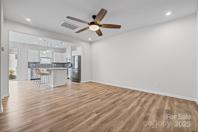 15626 Little Bluestem St, Charlotte, NC 28278 - kitchen featuring appliances with stainless steel finishes, a kitchen bar, a ceiling fan, white cabinetry, and light wood finished floors