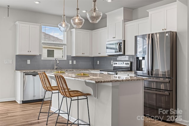 15626 Little Bluestem St, Charlotte, NC 28278 - kitchen with stainless steel appliances, tasteful backsplash, a center island, white cabinets, and a kitchen bar