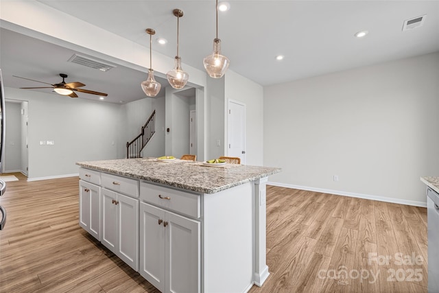 15626 Little Bluestem St, Charlotte, NC 28278 - kitchen with light wood-style flooring, hanging light fixtures, ceiling fan, a kitchen island, and light stone countertops