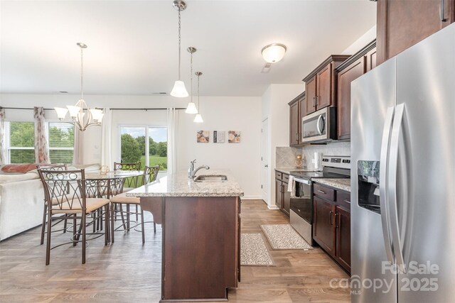 1111 Freeman View Dr, Albemarle, NC 28001 - kitchen featuring stainless steel appliances, an island with sink, tasteful backsplash, light wood-type flooring, and light stone counters
