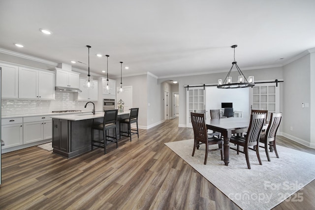 2019 Trailwood Dr, Matthews, NC 28104 - dining area featuring a barn door, arched walkways, dark wood-style floors, recessed lighting, and ornamental molding