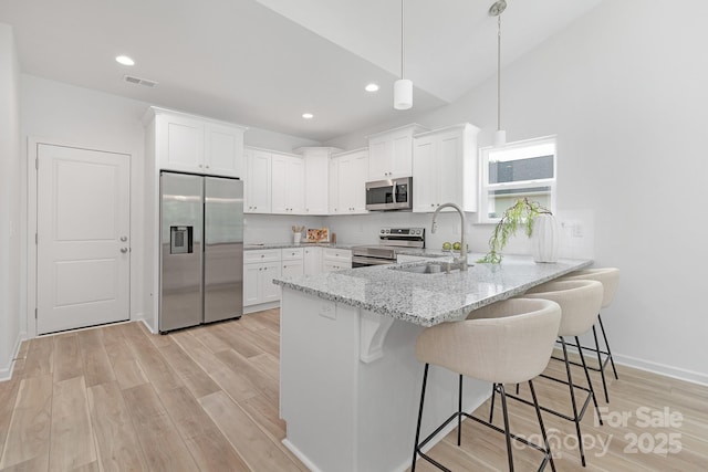 4478 Pebblebrook Cir SW, Concord, NC 28027 - kitchen with stainless steel appliances, a peninsula, white cabinets, light wood-style floors, and recessed lighting